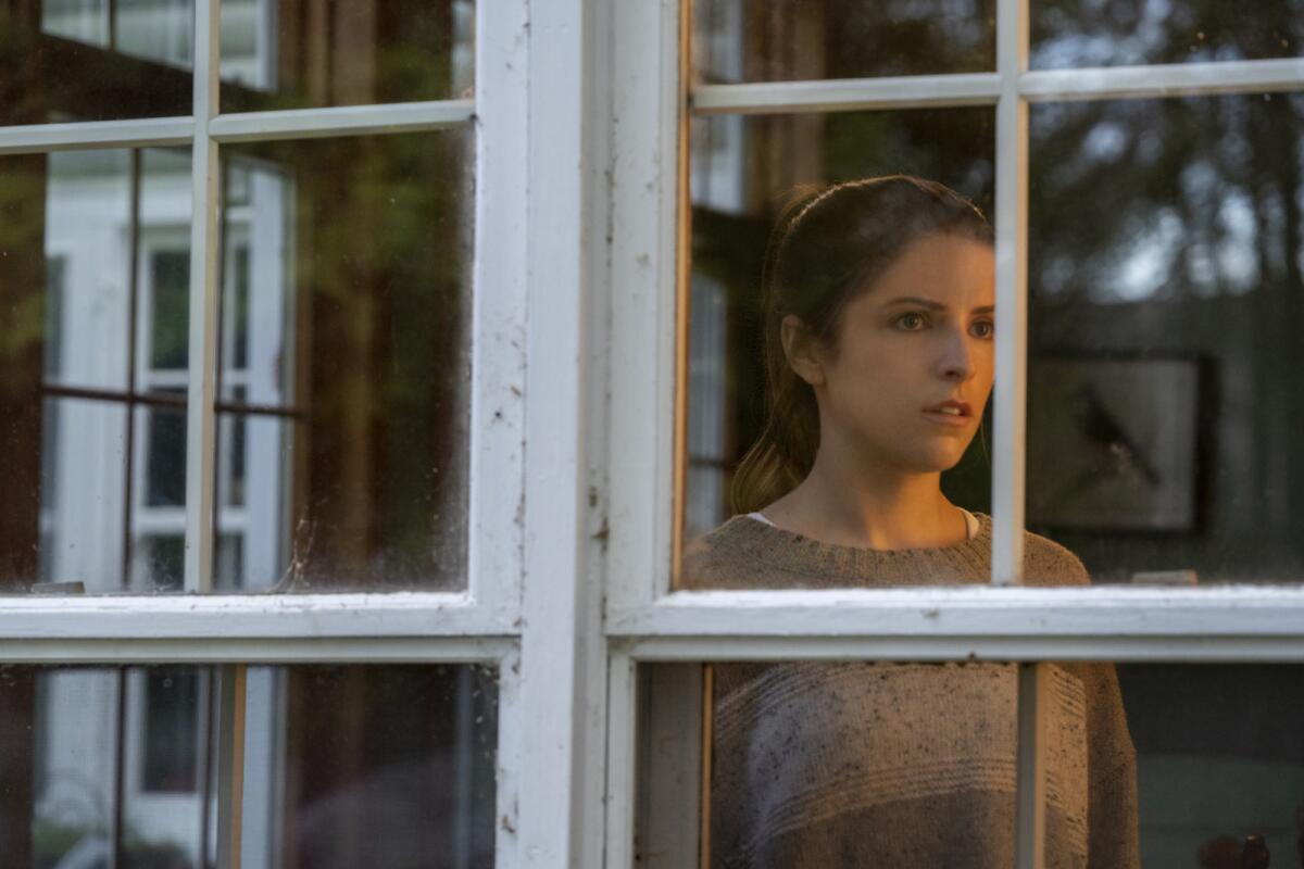 A woman looks anxiously through windowpanes that resemble cell bars.