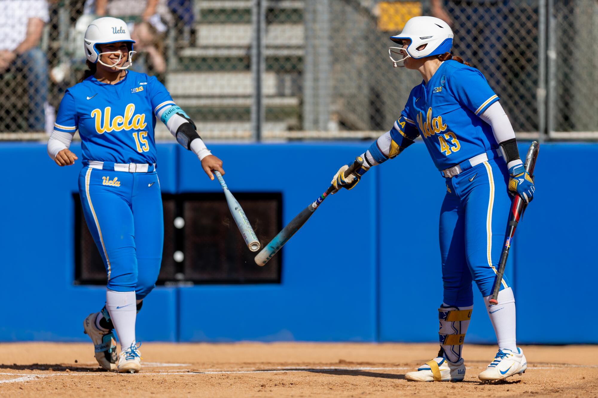 UCLA softball players Jordan Woolery, left, and Megan Grant touch bats before Woolery goes up to bat earlier this season.