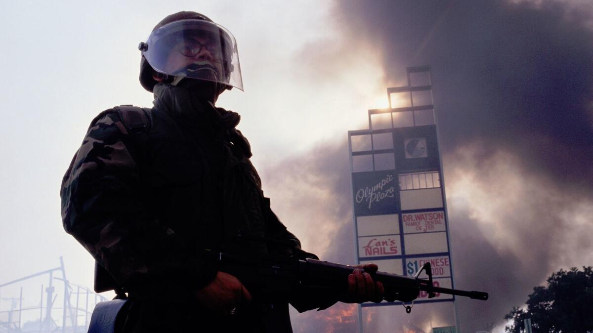 A member of the National Guard stands near burning building during the Los Angeles riots in 1992.