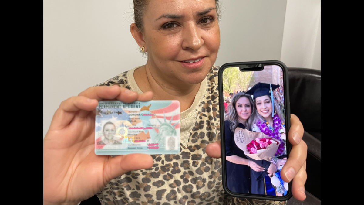 Delia sostiene a lo que llama dos tesoros en sus manos, la foto de su tarjeta de residencia y la foto de su hija Andrea.