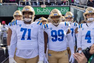 UCLA players Raiqwon O'Neal and Jacob Sykes lead the team onto the field 