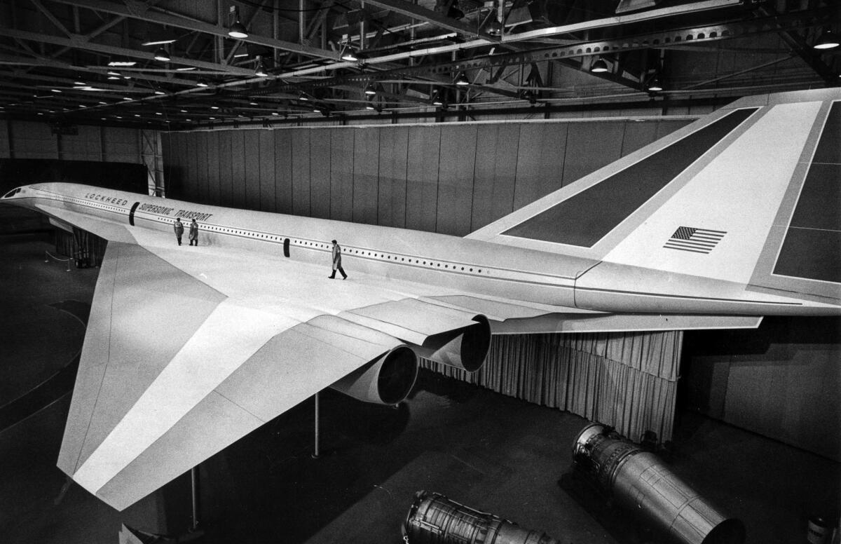 June 27, 1966: Three technicians walk on the left delta wing of the full-scale mock-up of the proposed Lockheed supersonic transport that stretches 273 feet from nose to tail.