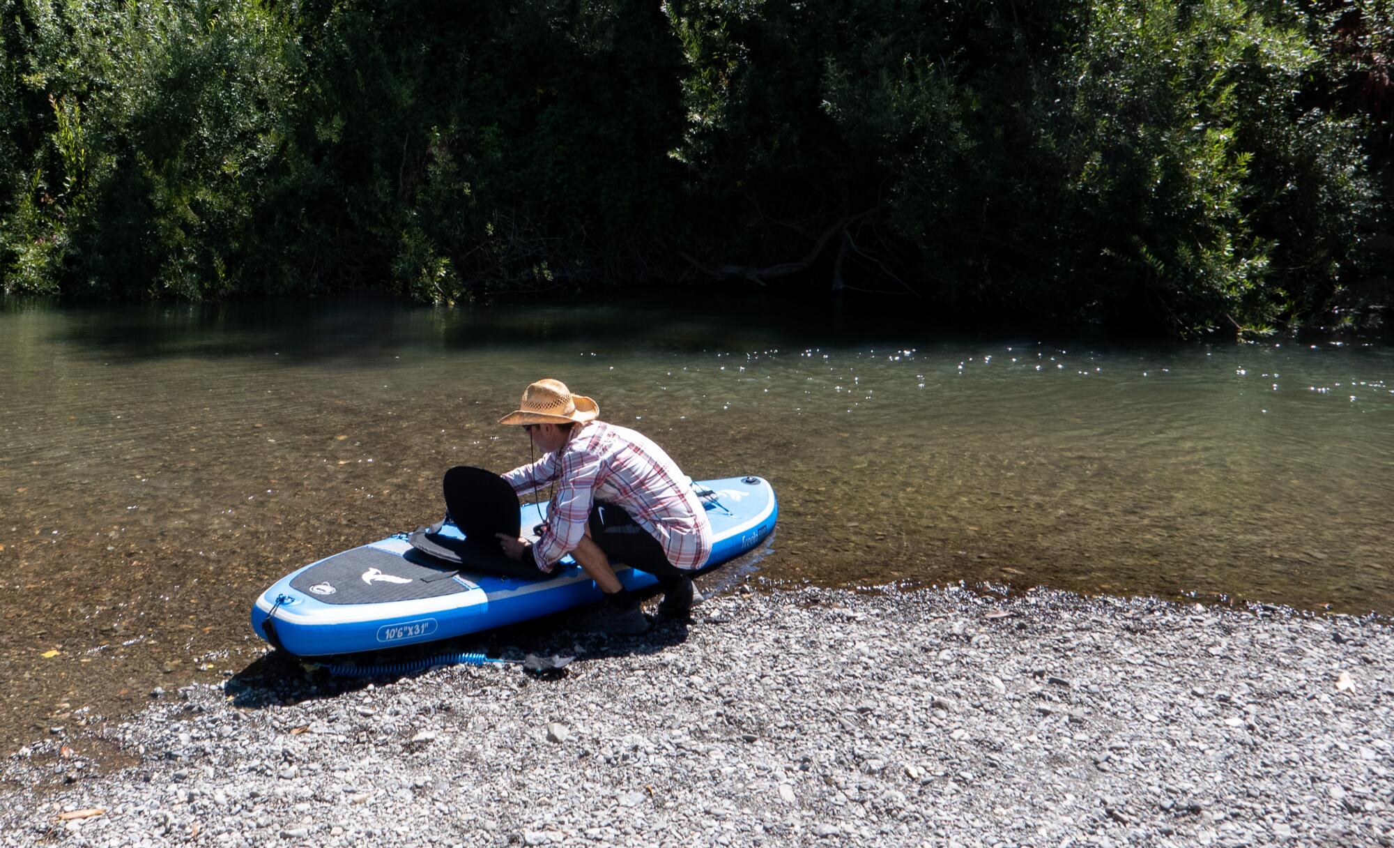 A visitor prepares his kayak on the Russian River shoreline.