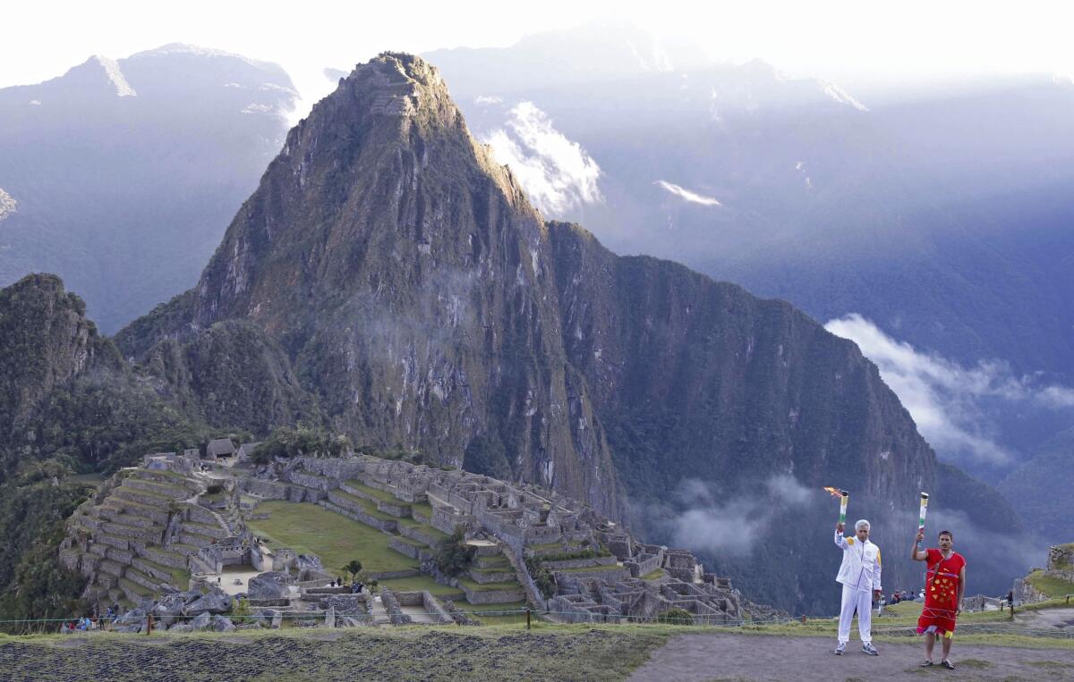 In this handout photo provided by the Lima2019 Pan American Sports Organization, Peru's Culture Minister Fernando Astete Victoria, in white, takes part in a ceremony marking the arrival of the Pan Am flame to the Machu Picchu archeological site in Cuzco, Peru, Thursday, July 4, 2019. The Pan American Games begin July 26 and run through Aug. 11, 2019, in Lima. (German Falcon/Lima2019 Pan American Sports Organization via AP)