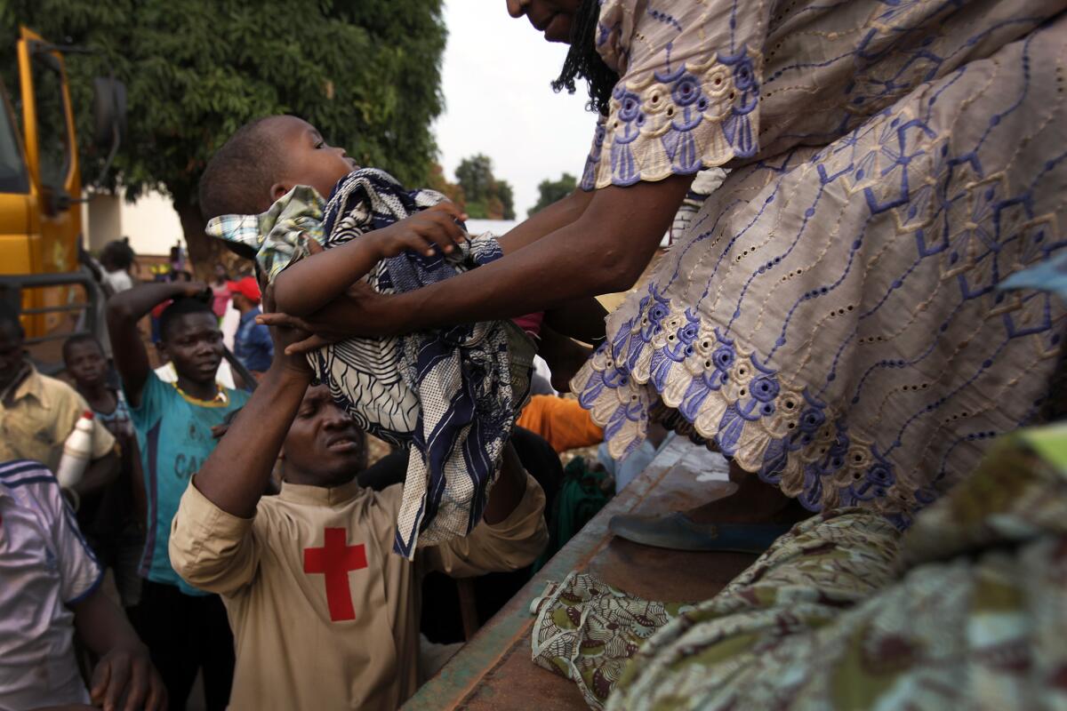 Father Bernard Kenvi hoists a Muslim child into a truck in Bossemptele as much of the Muslim population flees the area under threat of violence from mostly Christian militias.