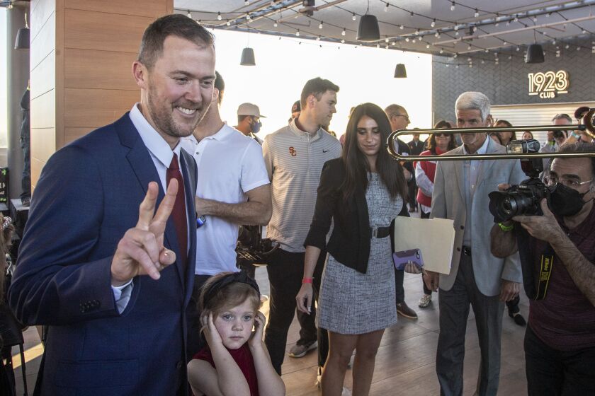 LOS ANGELES, CA - November 29 2021: Lincoln Riley flashes Trojan sign as his youngest daughter Stella, 5, plugs her ears as Trojan band plays after he was announced as the new head football coach at USC during a press conference at the Coliseum on Monday, Nov. 29, 2021 in Los Angeles, CA. (Brian van der Brug / Los Angeles Times
