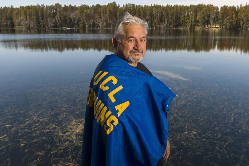 Zenon Andrusyshyn dons his UCLA football raincoat, at his home in Land O' Lakes, Fla. The son of Ukrainian parents, Andrusyshyn was born in a German refugee camp and migrated with his family to Canada when he was 3 years old.