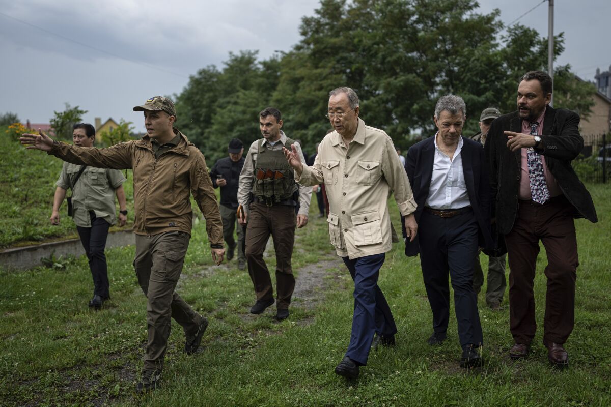 Former U.N. Secretary-General Ban Ki-moon, centre, and former Colombia's President Juan Manuel Santos, centre right, walk during their visit in Bucha near Kyiv, Ukraine, Tuesday, Aug. 16, 2022. The former leader of the United Nations called on the world Tuesday to honour civilian victims killed during the Russian attack on Kyiv. (AP Photo/Evgeniy Maloletka)