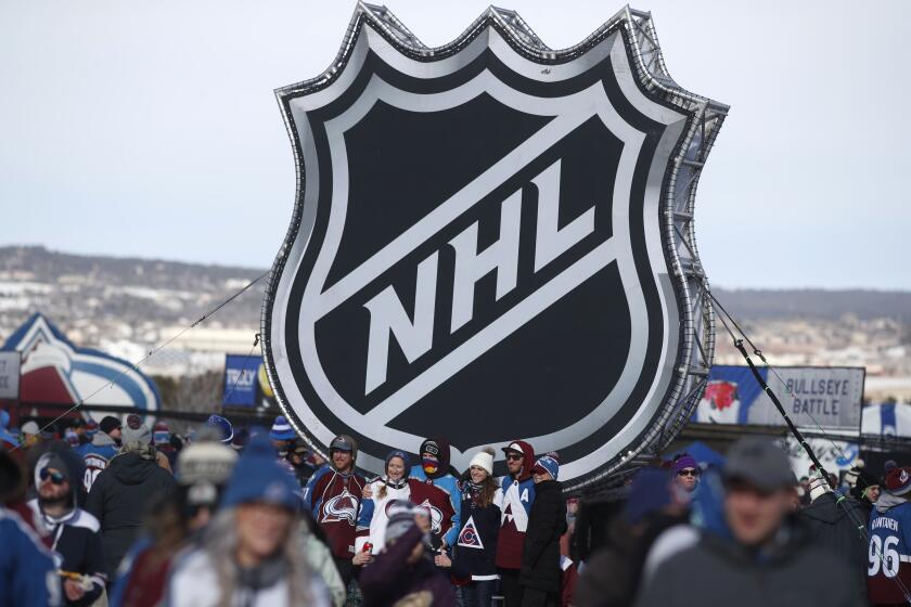 FILE - In this Saturday, Feb. 15, 2020, file photo, fans pose below the NHL league logo.