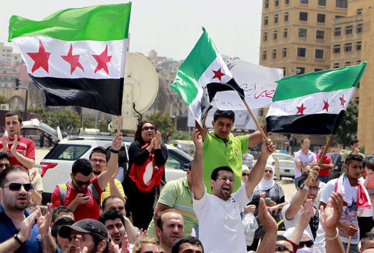 Lebanese and Syrian activists hold Syrian revolution flags during a protest in Beirut against the participation of Hezbollah in the Syrian war.