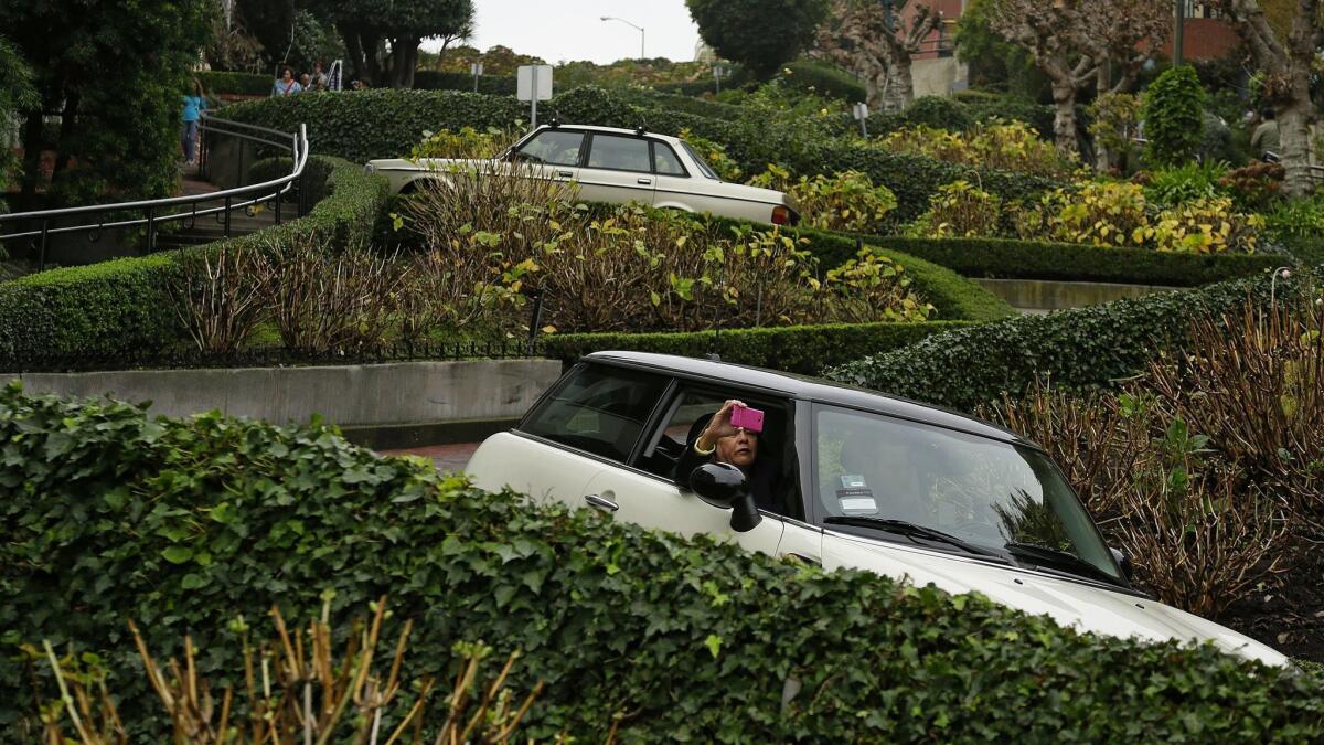 A woman takes a selfie while riding down the crooked section of Lombard Street in San Francisco. The street with eight hairpin turns draws about 2 million drivers a year.