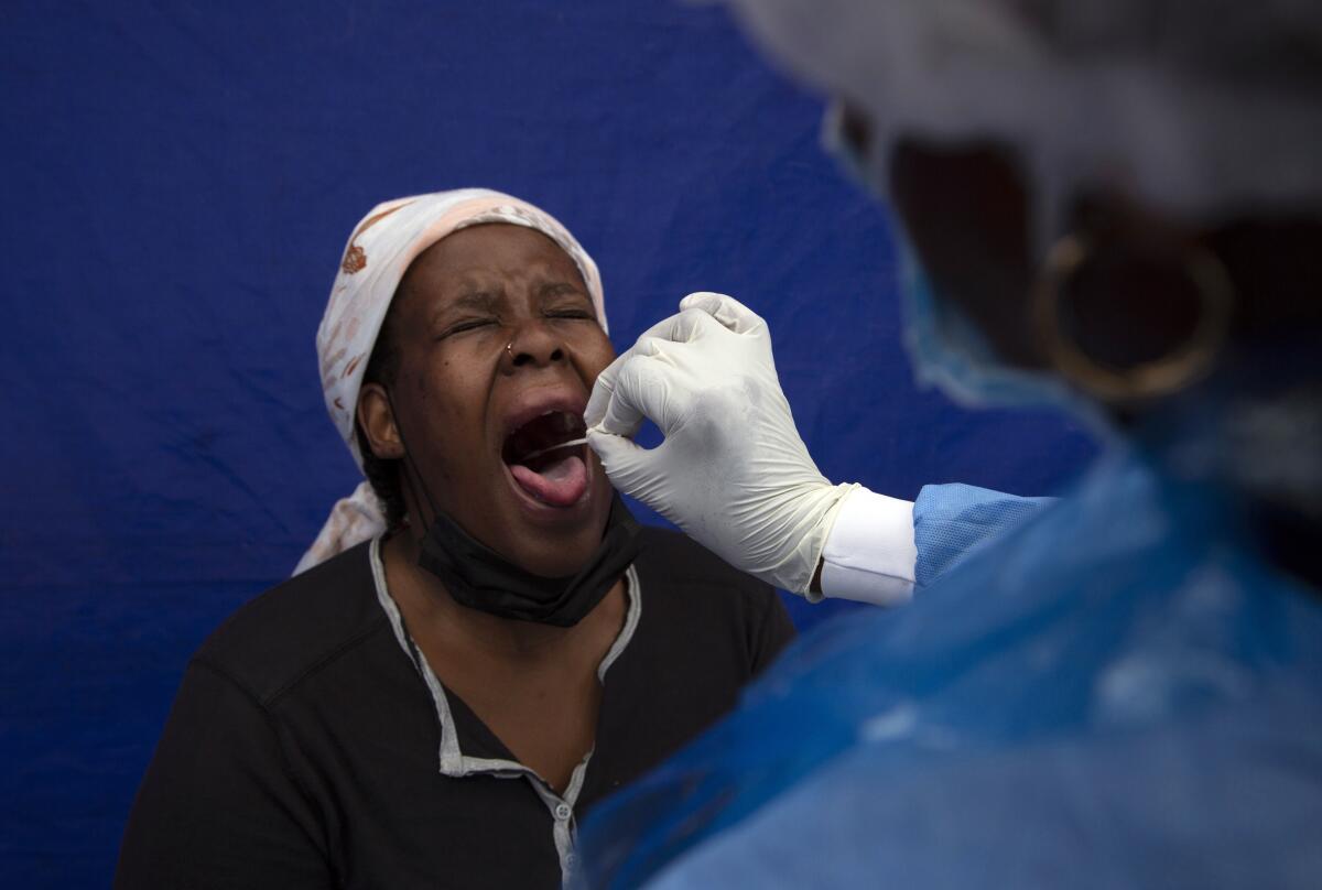 Una mujer es sometida a frotis de garganta por un trabajador médico