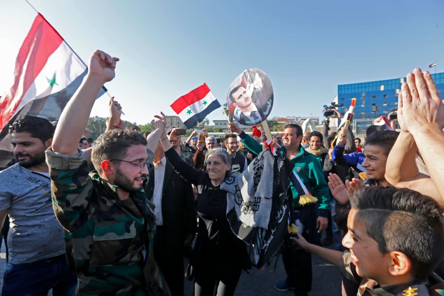 Syrians wave the national flag and portraits of President Bashar Assad as they gather in Damascus after the airstrikes.