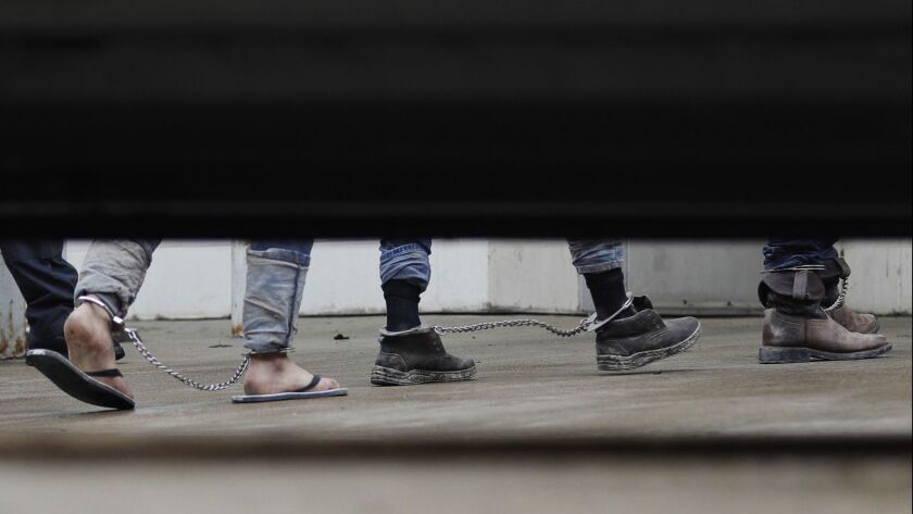 Immigrants in ankle chains disembark from a bus for hearings at the federal courthouse in McAllen, Texas, on Friday.
