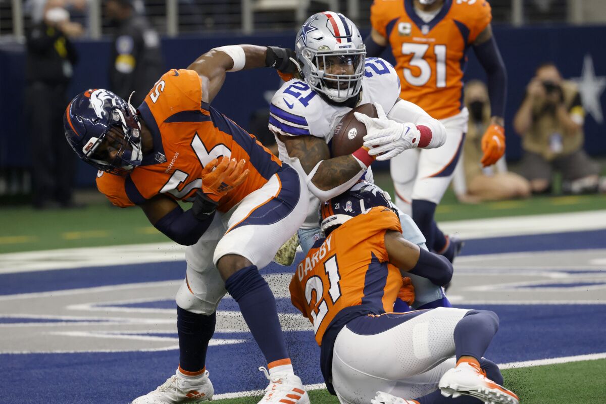 Denver Broncos' Baron Browning (56) and Ronald Darby, bottom, defend as Dallas Cowboys running back Ezekiel Elliott (21) scores on a two point conversion in the second half of an NFL football game in Arlington, Texas, Sunday, Nov. 7, 2021. (AP Photo/Ron Jenkins)
