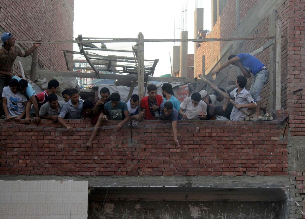 Residents look on as a mob in the Egyptian village of Zawyat Abu Musalam attacked Shiite Muslim men gathered in a house.