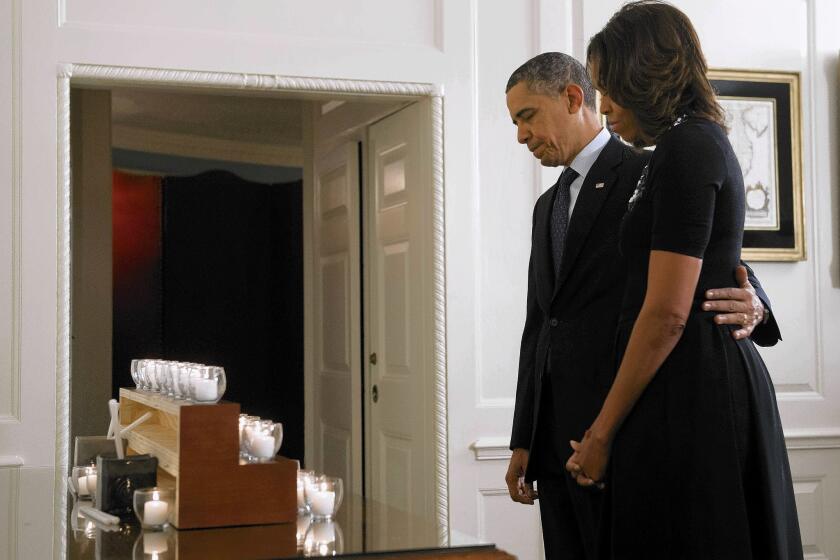 President Obama and First Lady Michelle Obama take a moment of silence for the 26 killed a year ago Saturday at Sandy Hook Elementary School. Gun safety legislation fell short in Congress after the massacre.