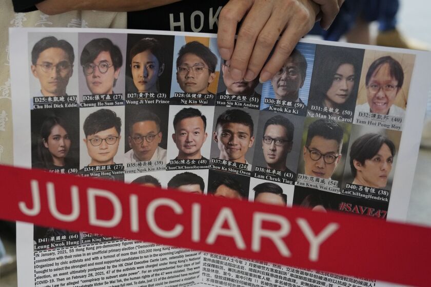 FILE - A supporter holds a placard with the photos of some of the 47 pro-democracy defendants outside a court in Hong Kong, on July 8, 2021. Some of Hong Kong’s best-known pro-democracy activists went on trial Monday, Feb. 6, 2023, in the biggest prosecution yet under a law imposed by China’s ruling Communist Party to crush dissent. The 18 defendants face up to life in prison if convicted under the national security law critics say is eroding the autonomy promised when Hong Kong returned to China in 1997, and its status as a global business center. They were among 47 pro-democracy figures who were arrested in 2021 under the legislation that was imposed following protests in 2019. They were charged in connection with an informal 2020 primary election. (AP Photo/Kin Cheung, File)