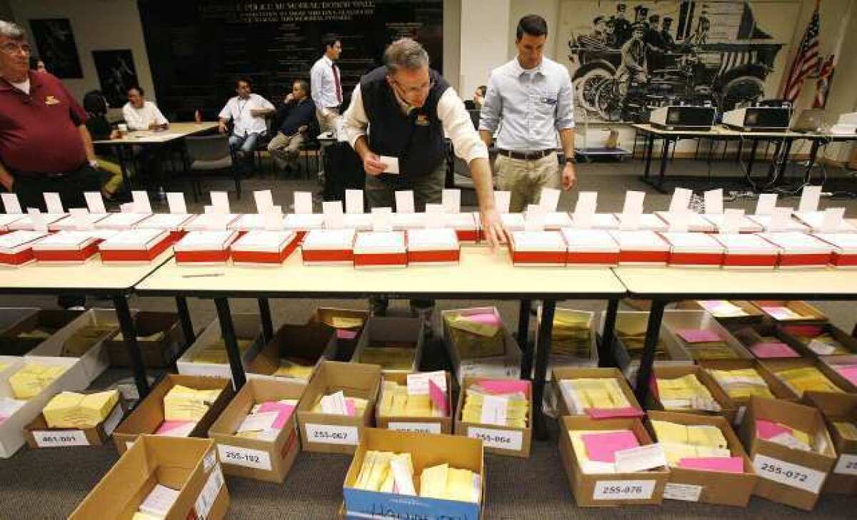 A worker puts leader cards in the red ballot boxes with absentee ballots in the Community Room at the Glendale Police Department on Election Day in Glendale.