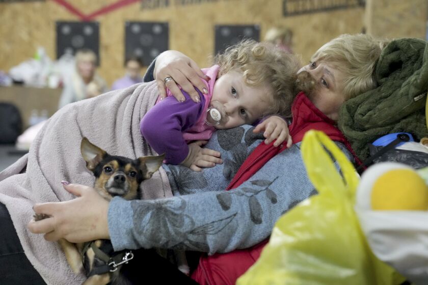 A women holds a child and a dog in a shelter inside a building in Mariupol, Ukraine, Sunday, Feb. 27, 2022. Street fighting broke out in Ukraine's second-largest city and Russian troops squeezed strategic ports in the country's south as the prospect of peace talks remains uncertain. (AP Photo/Evgeniy Maloletka)