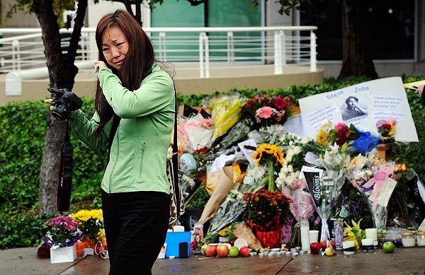 Christine Gng, the wife of an Apple employee, cries Wednesday after taking a picture of the makeshift memorial for Steve Jobs at the Apple headquarters in Cupertino, Calif. Jobs co-founded Apple in 1976 and is credited with marketing the world's first personal computer in addition to the popular iPod, iPhone and iPad.