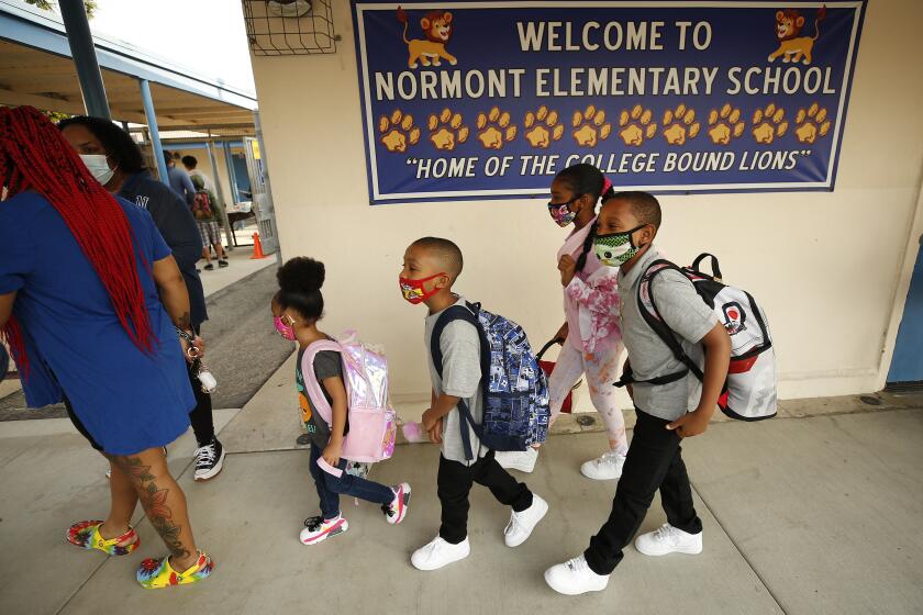 HARBOR CITY, CA - AUGUST 16: Mother Ladayna Jordan, left, leads her children, Alayna, Aedan, Aaliyah and Ahmier Davis, left to right, to the front door of Normont Elementary School on the first day of in class instruction on August 16, as LAUSD officials welcome students, teachers, principals, at various school sites across Los Angeles. For the younger students it will be their first time in a classroom. Normont Elementary on Monday, Aug. 16, 2021 in Harbor City, CA. (Al Seib / Los Angeles Times).
