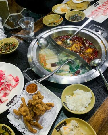 A metal bowl with a divider in the center, surrounded by small dishes of rice and other items