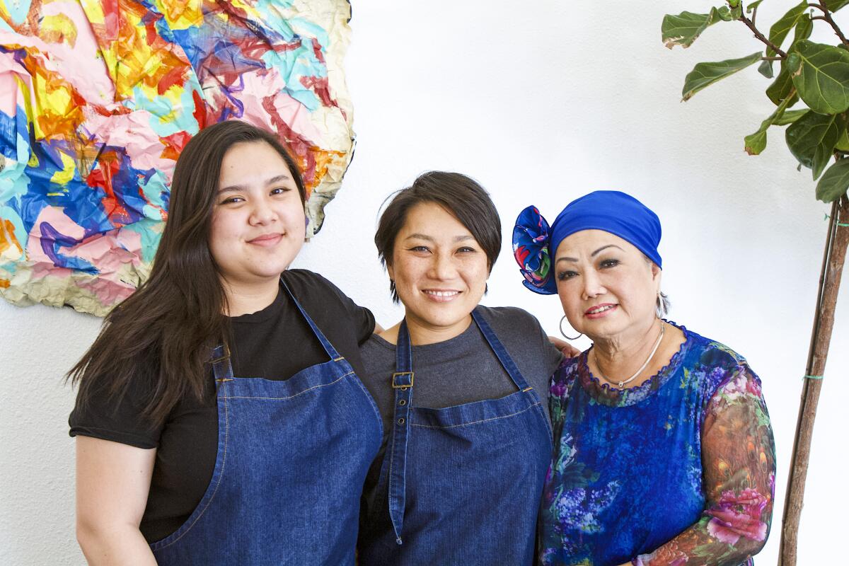 Three women stand in a restaurant dining room.