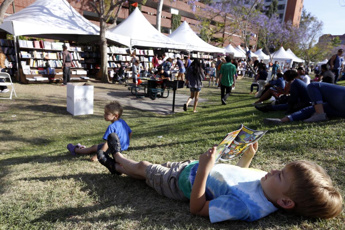 A young reader relaxes on the grass at the Los Angeles Times Festival of Books on the USC campus on April 19.