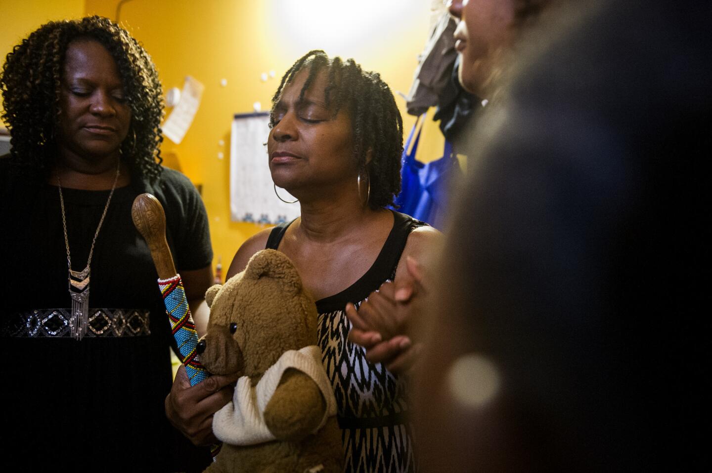 Najiyyah Avery, center, prays for her son, Jai "Jerry" Williams, while holding his childhood teddy bear at the Block off Biltmore in Asheville, N.C., on July 12, the day Williams would have turned 36. Williams was fatally shot by police at the city's Deaverview Apartments 10 days earlier.