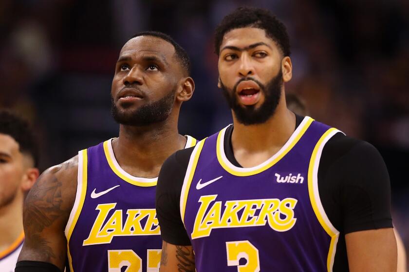 PHOENIX, ARIZONA - NOVEMBER 12: LeBron James #23 of the Los Angeles Lakers stands between Devin Booker #1 of the Phoenix Suns and Anthony Davis #3 during the second half of the NBA game at Talking Stick Resort Arena on November 12, 2019 in Phoenix, Arizona. The Lakers defeated the Suns 123-115. NOTE TO USER: User expressly acknowledges and agrees that, by downloading and/or using this photograph, user is consenting to the terms and conditions of the Getty Images License Agreement (Photo by Christian Petersen/Getty Images)