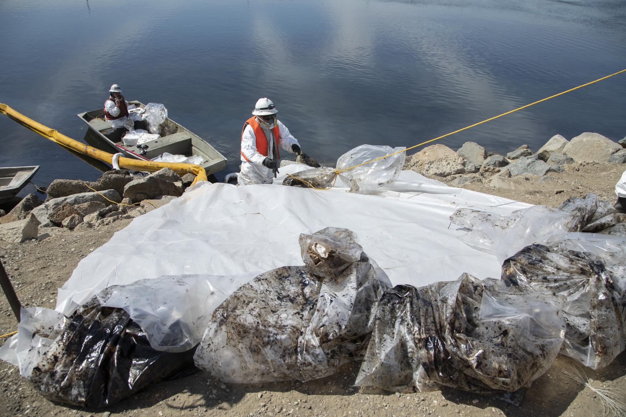Workers with Patriot Environmental Services collect bags of oil-soaked pads and other debris during cleanup at Talbert Marsh.
