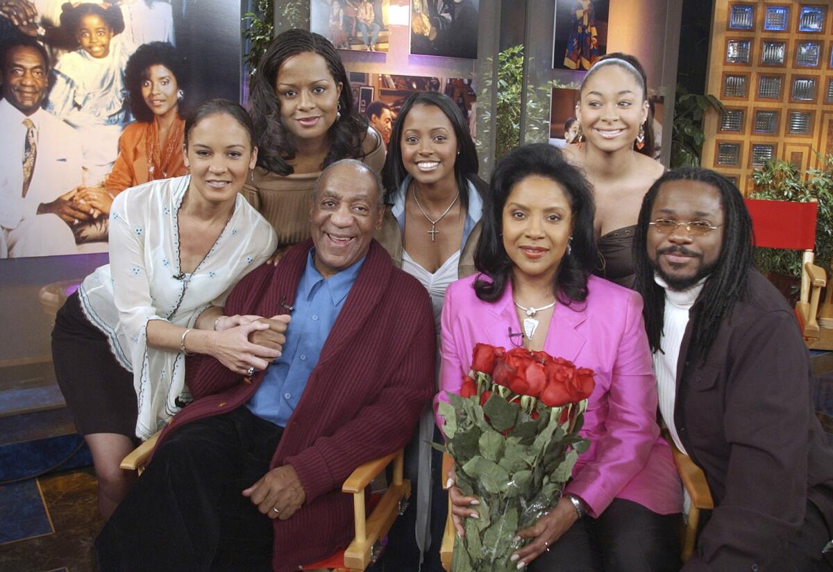 A group of men and women pose for a portrait while sitting in chairs