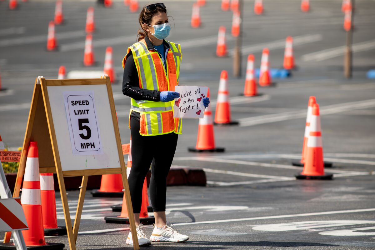 A woman in a mask and reflective vest holding a sign