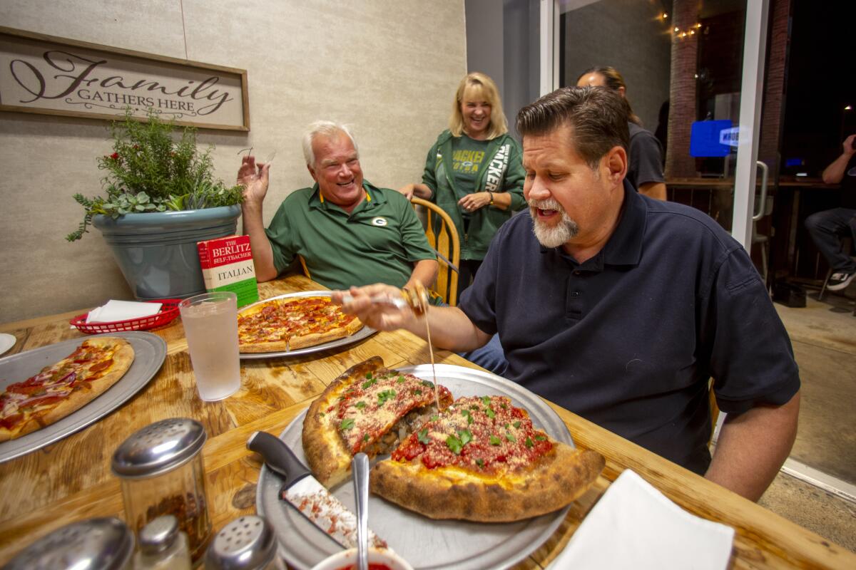 Huntington Beach Mayor Erik Petersen digs into a 6-pound calzone Sunday in the company of Bob and Linda Wentzel at Stoney’s Pizza.