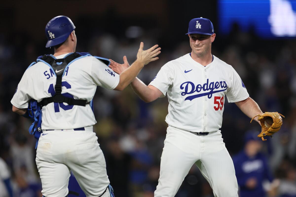 Dodgers pitcher Evan Phillips slaps hands with Will Smith after closing out a 4-1 win over the Rockies.