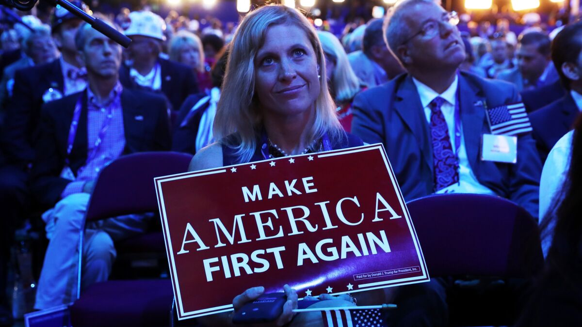 A delegates holds up signs that read "Make America First Again" during the opening of the third day of the Republican National Convention on July 20, 2016.