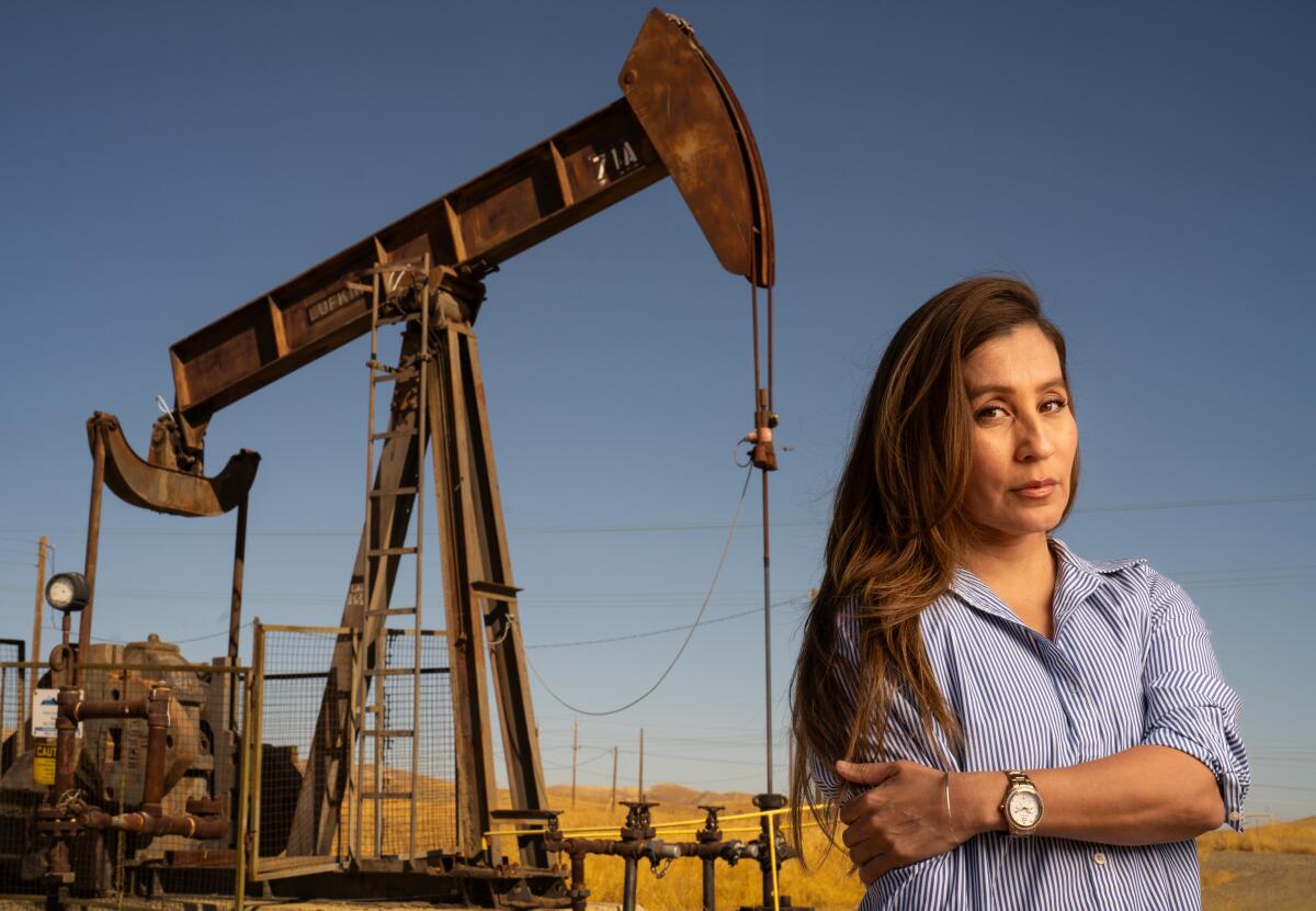 Argelia Leon stands near an oil pumpjack in Coalinga. 