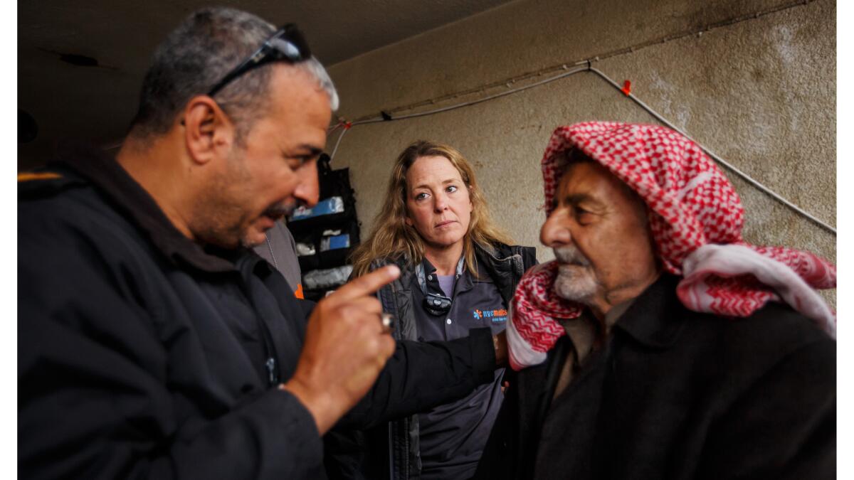 Maj. Tarek Gazali, left, translates the urgency of Kathy Bequary's instructions to go to a hospital to treat the infected burn wound on Jadwaa Hamad, right, that could lead to the loss of his leg.