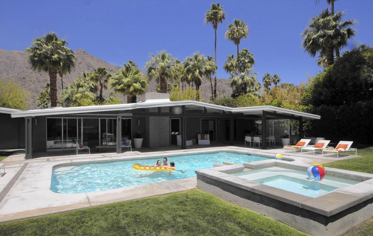 Rob Hoyt plays with his son, Lewis, and daughter, Ellie, in the pool at their midcentury home in Palm Springs, designed by William Krisel.
