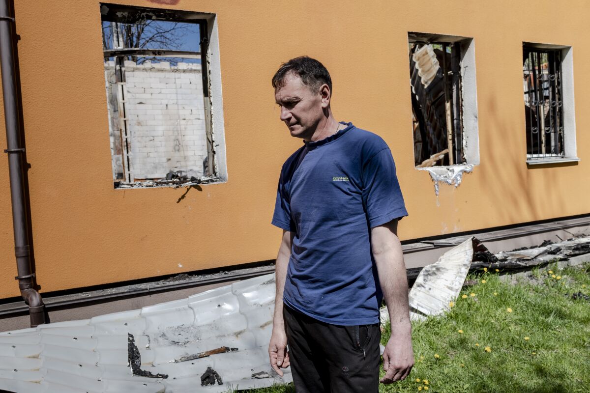 A man stands beside a ruined building.