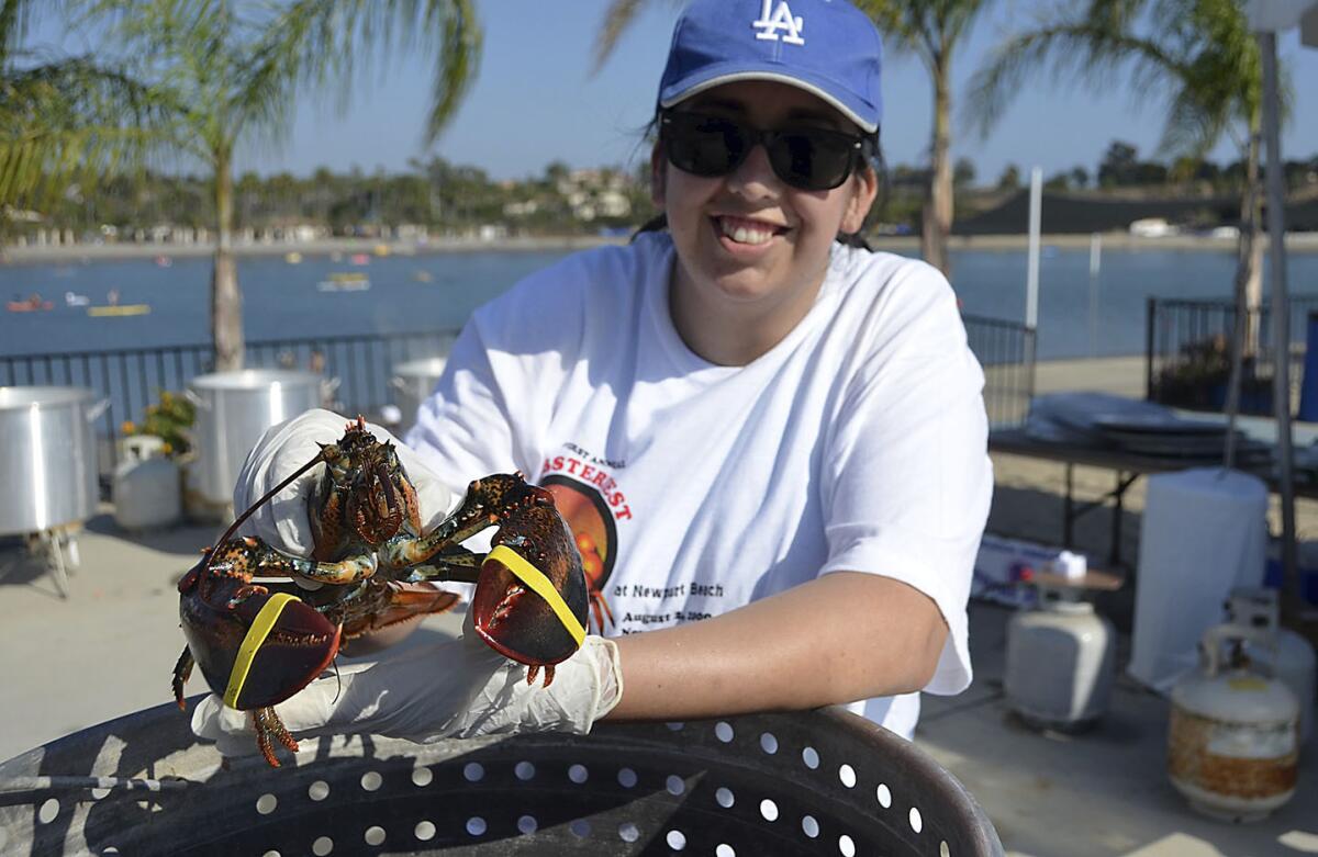 Lucia Martin takes hold of Larry the lobster during the sixth annual Lobsterfest held Sunday at the Dunes Waterfront Resort. Proceeds will help the Make A Wish of Orange County and the Inland Empire, Leadership Tomorrow and New Directions for Women.