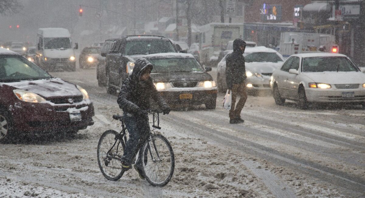 A pedestrian and cyclist join vehicles on Flatbush Avenue during a slushy snowfall in Brooklyn on March 5. New Yorkers this winter endured one of the coldest, snowiest seasons in decades.
