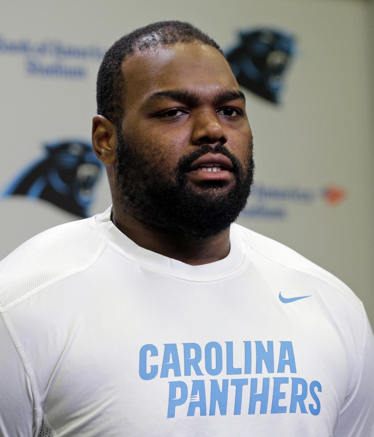 Michael Oher poses in a white Carolina Panthers shirt