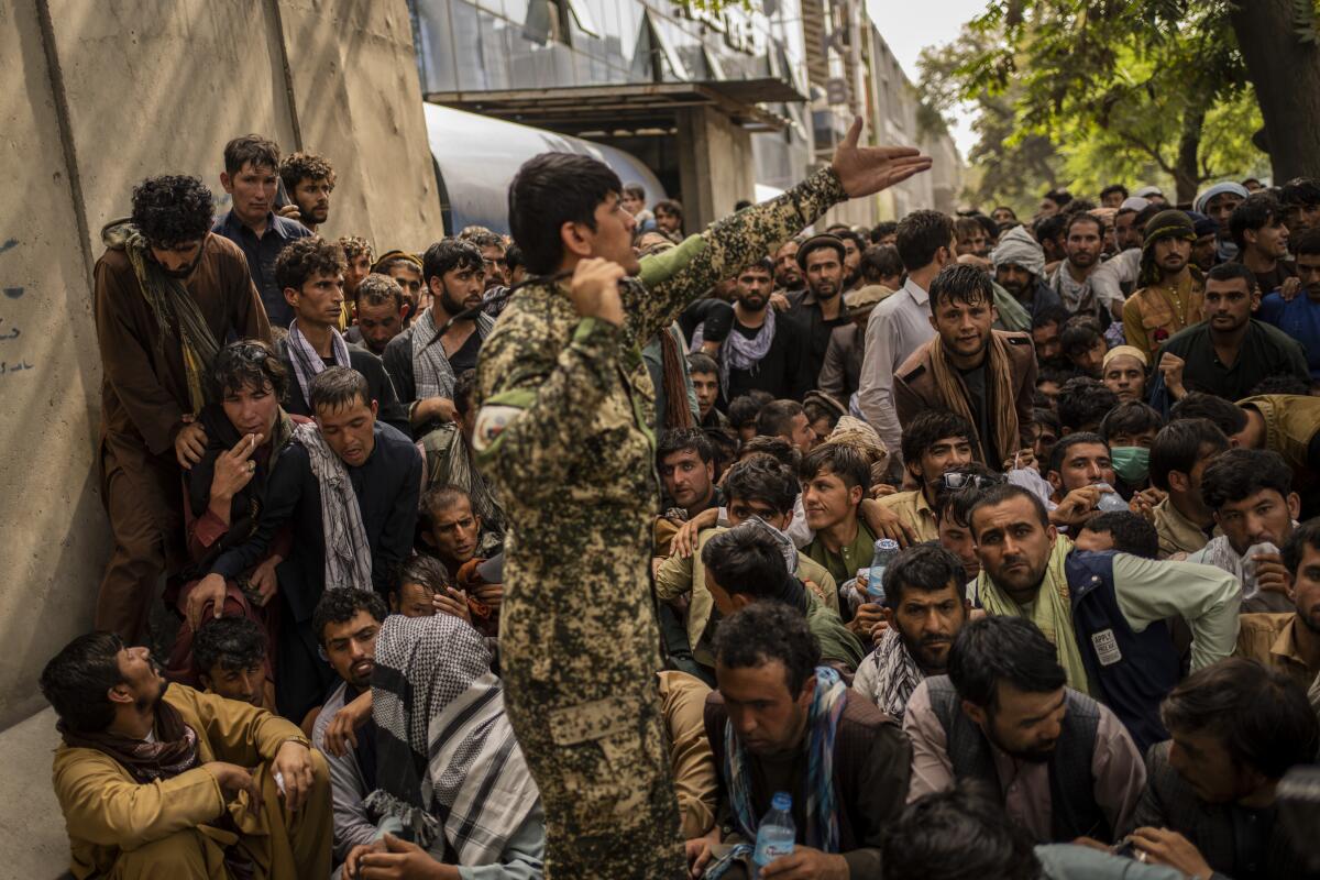 Afghans wait in front of a bank as they try to withdraw money in Kabul, Afghanistan.