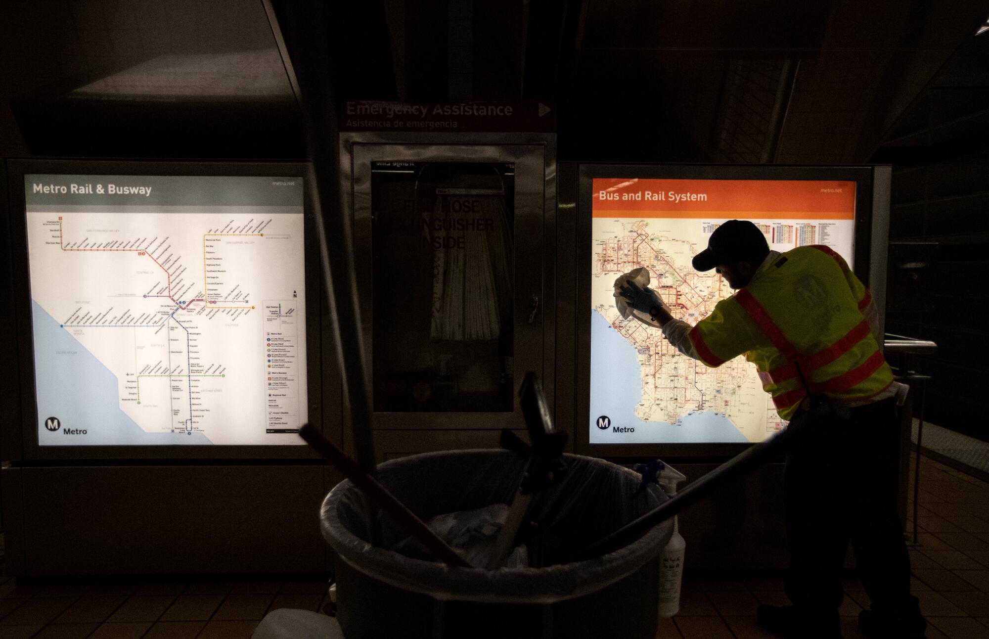 An L.A. Metro custodian cleans a transit map inside the North Hollywood station.
