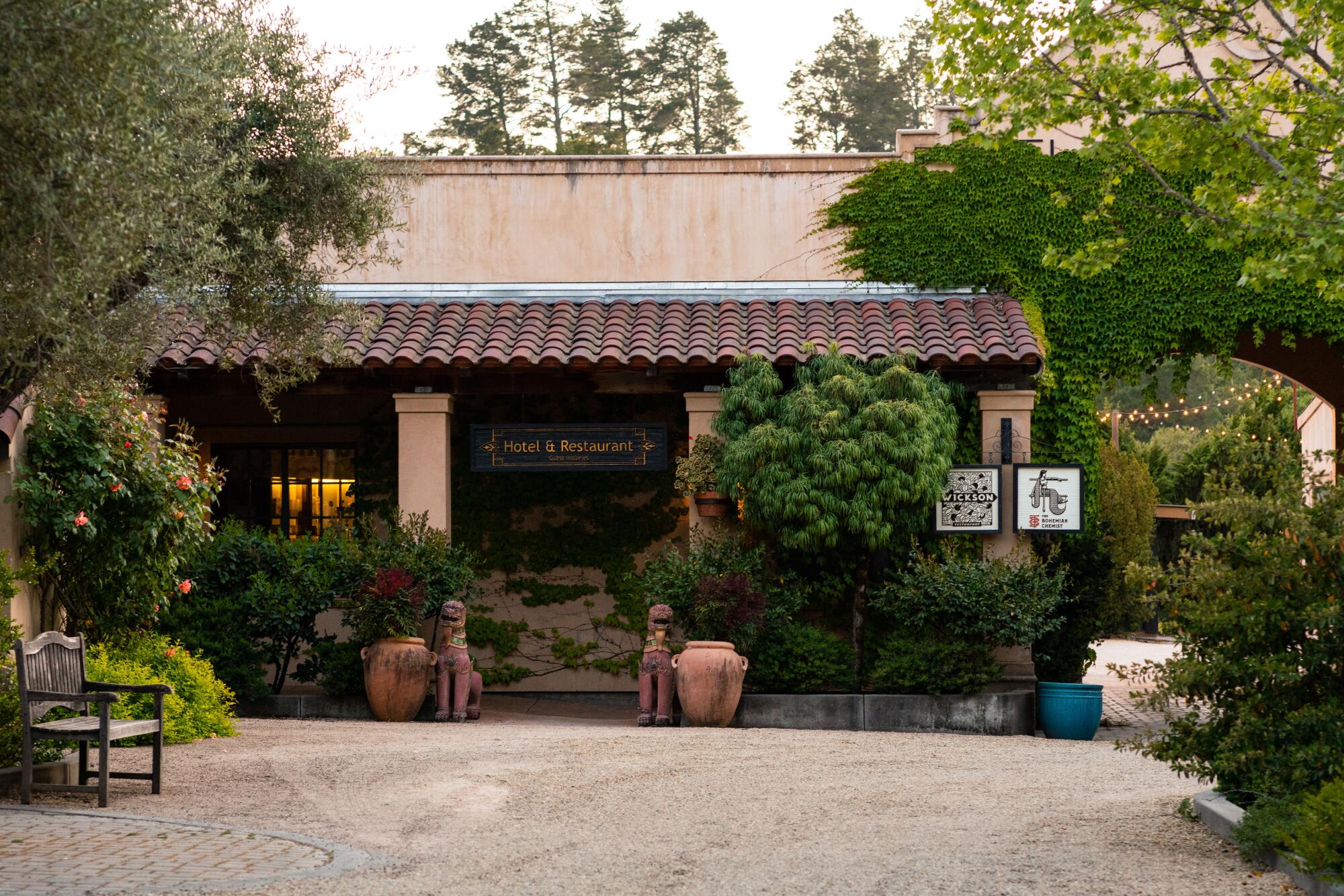The exterior of a boutique hotel with a stucco tile roof and surrounded by lush greenery.