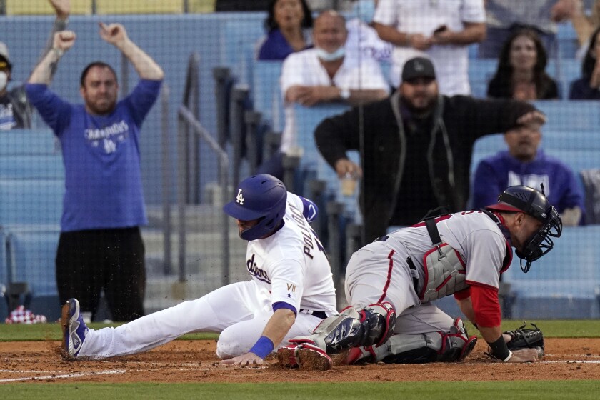 Los Angeles Dodgers' AJ Pollock, left, scores on a single by Zach McKinstry as Washington Nationals catcher Yan Gomes can't hold on to the throw during the second inning of a baseball game Saturday, April 10, 2021, in Los Angeles. (AP Photo/Mark J. Terrill)