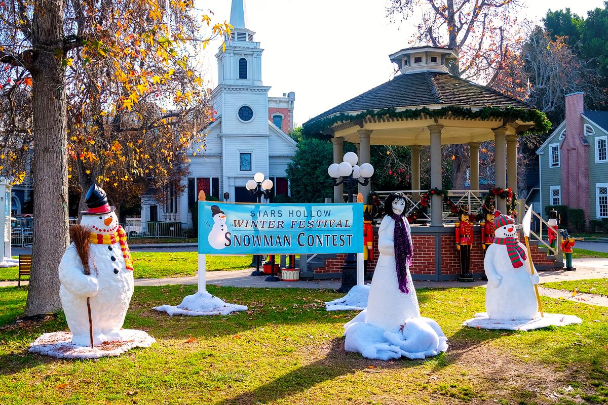 A gazebo covered in Christmas decorations with fake snowmen standing around.