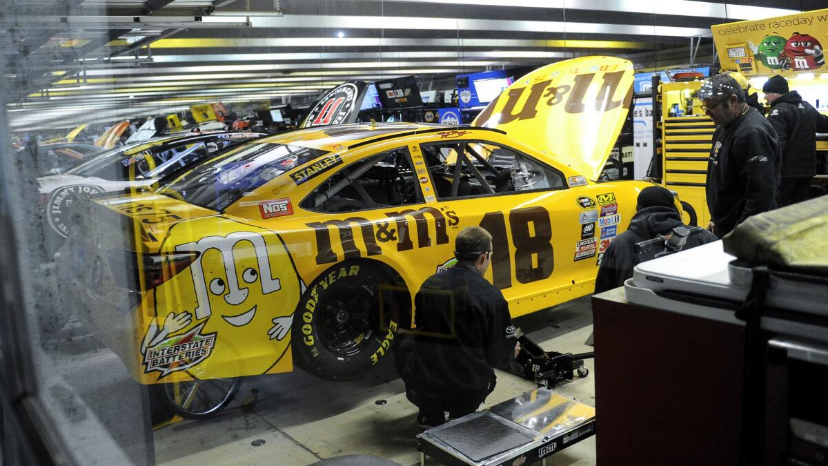 Crew members work on Kyle Busch's No. 18 car after it failed a post-qualifying inspection on Friday.